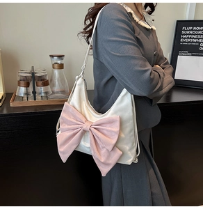 Detail of pink satin bow on white shoulder bag worn by model in a modern interior