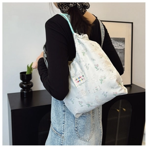 Détail du sac à cordon en toile avec imprimé fleuri et lapin et bandoulière en corde