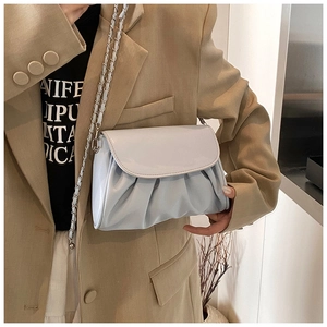Detail of light blue pleated patent leather bag with silver chain strap on model