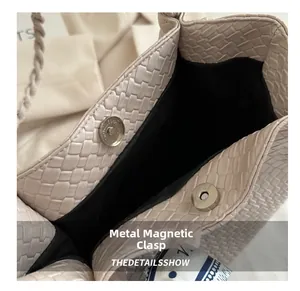 Detail of woven leather tote bag featuring a silver magnetic snap closure and polka dot scarf