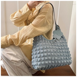 Detail of light blue bubble textured shoulder bag with a floral charm on a model