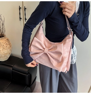 Detail shot of the large 3D bow design on this pink soft leather shoulder bag for women
