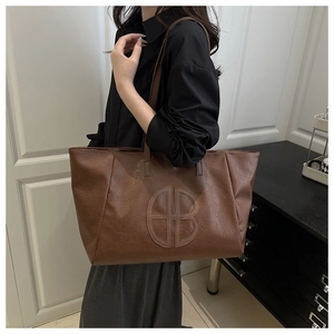 Detailansicht der Logoprägung und weichen Lederstruktur einer braunen XXL-Shopper-Tasche