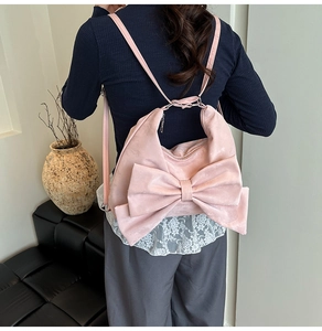 Pink sweet shoulder bag with large bow detail shown from a rear model view