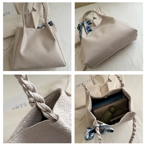 Detail view of beige woven tote bag with braided handles and floral silk scarf accessory