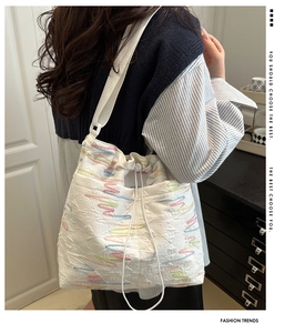Detail of white pleated nylon tote bag with colorful wave embroidery and drawstring closure