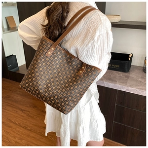 Detail of vintage brown tote bag with geometric print and gold rivets on shoulder strap