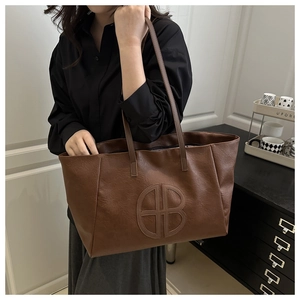 Detail einer großen braunen Shopper-Tasche aus strukturiertem Leder mit Logo-Prägung
