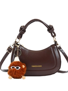 Dark brown faux leather crescent saddle bag with plush charm and knot detail