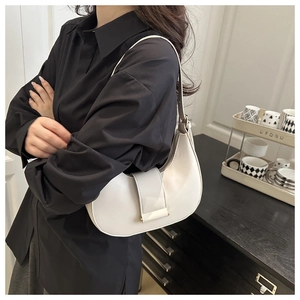 Detail of a creamy white leather hobo bag with a gold buckle worn with a black shirt
