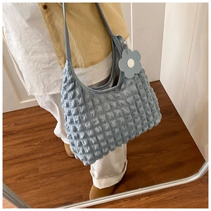 Detail of light blue bubble textured shoulder bag with floral charm on a female model