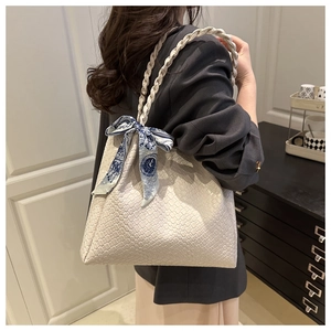 Detail of white woven tote bag with braided handle and blue floral silk scarf accessory