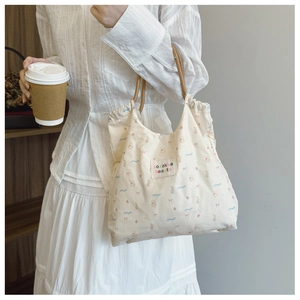 Detail of floral canvas tote bag featuring cute cartoon rabbit and strawberry prints