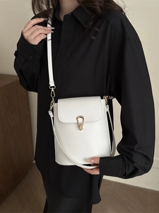Minimalist white bucket bag with golden teardrop buckle on a black shirt model