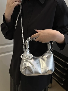 Metallic silver handbag with pearl bow charm and chain strap shown on model shoulder