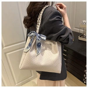 Close-up of beige tote bag with woven texture and elegant blue patterned silk ribbon