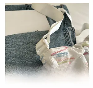 Dettaglio di ricamo arcobaleno su una borsa a secchiello bianca trapuntata con tracolla