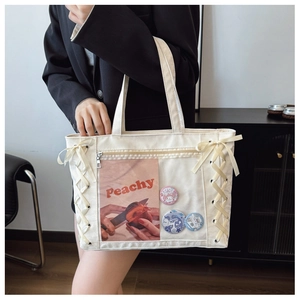 Detail of white tote bag featuring side ribbon lace-up and transparent display window