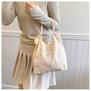Close-up of pink floral drawstring tote bag with soft fabric and woven handle detail