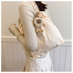 Detail of pink drawstring backpack with cute rabbit print and brown alpaca plush charm