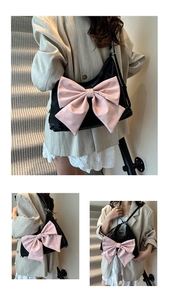 Detail of black shoulder bag with large pink bow featuring satin fabric and adjustable strap