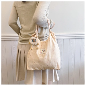 Detail of floral tote bag with drawstring closure and cute plush sheep pendant