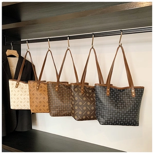Five styles of retro printed tote bags hanging neatly in a wardrobe professional setting