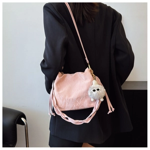 Pink slouchy cloud bag with a plush monster charm shown in a stylish crossbody carry style