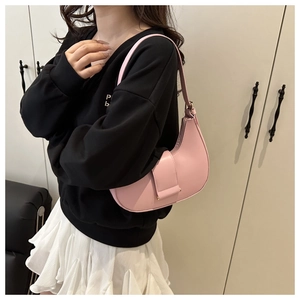 Close-up of pink semi-circular underarm bag showing smooth texture and magnetic flap detail
