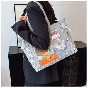 Detail of silver ita bag with clear window, side lace-up ribbons and plush charms