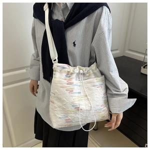 Dettaglio della borsa a secchiello in nylon trapuntato bianco con ricamo ondulato colorato