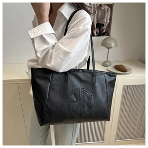 Detail der schwarzen Leder-Tote-Bag mit geometrischer Prägung getragen vom Model