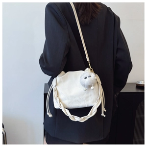 Detail of white leather bucket bag with woven handle and plush ball charm on a model