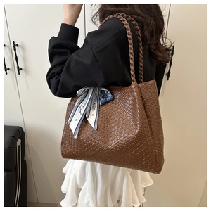 Detail of dark brown woven tote bag featuring a decorative Paris printed silk scarf