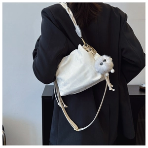 Detailed view of white drawstring cloud bag with plush pendant and gold metal buckle