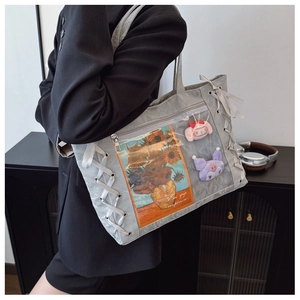 Detail view of the gray Ita bag with clear window featuring ribbons and charms
