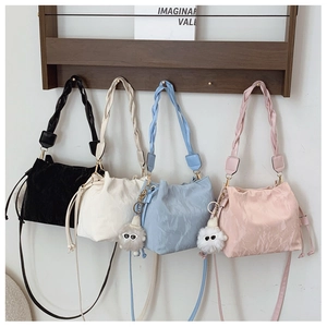 Detail of minimalist bucket bags in four colors with plush charms on a wall rack