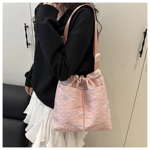 Detail view of quilted pink bucket bag with colorful rainbow wave pattern embroidery