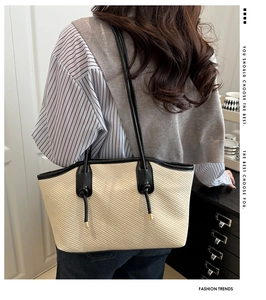 Détail du grand sac cabas tissé beige clair avec garniture en cuir noir et nœuds de sangle