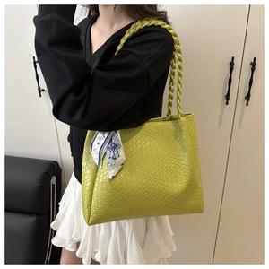 Detail view of woven lime green tote bag featuring a decorative patterned silk scarf handle