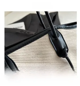 Detail of herringbone woven fabric tote bag with black leather trim and knotted handle