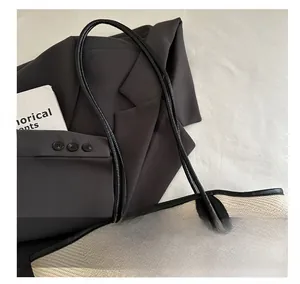 Close-up of woven bucket bag with black leather handle and elegant knot hardware details