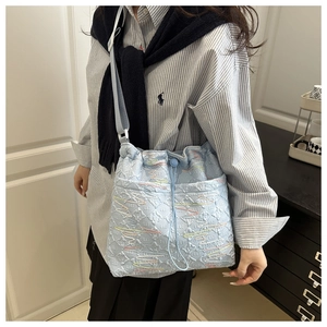 Detail of light blue jacquard bucket bag with colorful wavy embroidery and wide strap