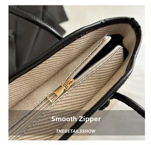 Macro detail of beige woven tote bag showing smooth gold zipper and black leather trim