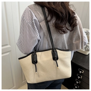 Detail of cream woven tote bag with black leather straps and stylish knot accents