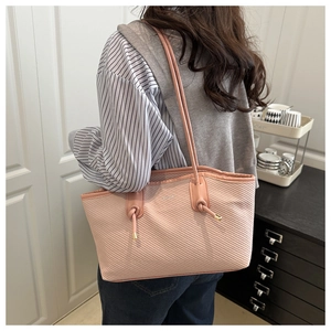 Pink tote bag detail showing textured fabric and leather strap with knot decor