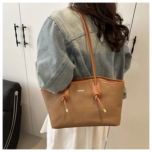 Detailed back view of a brown woven tote bag with leather straps and Fashion text