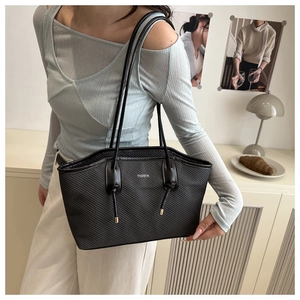 Detail of black tote bag with diagonal texture, white fashion text and dual slim straps