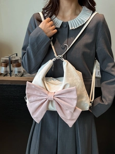 Chic cream tote bag with large pink bow and adjustable strap in lifestyle setting