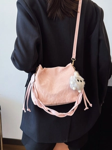 Pink pleated bucket bag for women with woven trim and cute white plush charm on model